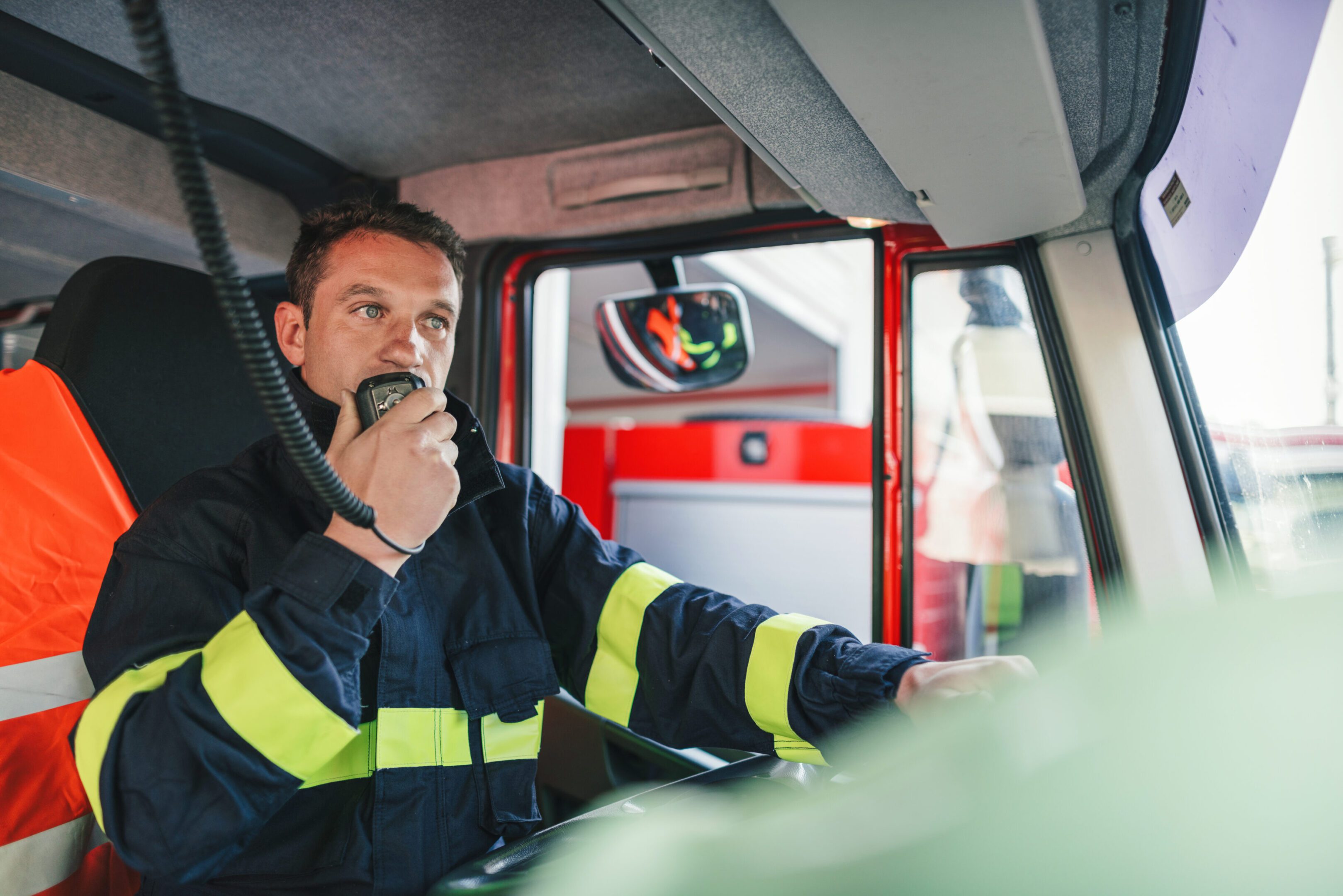Firefighter communicating in truck with radio.