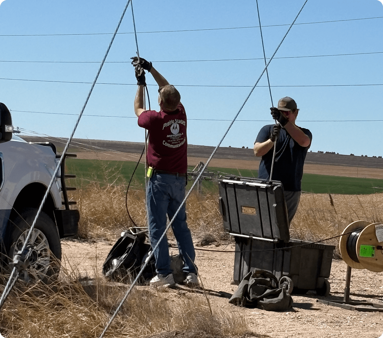Two people working on electrical wires outdoors.